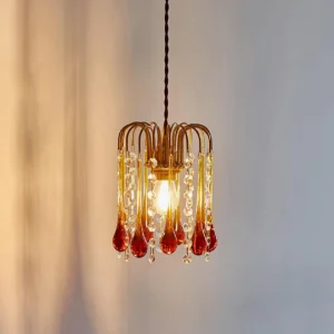 Lit Murano pendant light with warm glow, brass arms and cascading crystal beads, low angle view