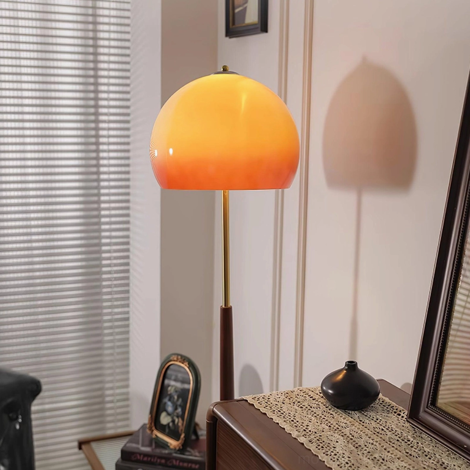 Close-up of mushroom floor lamp glowing caramel shade with gold metal accents and dark wood pole