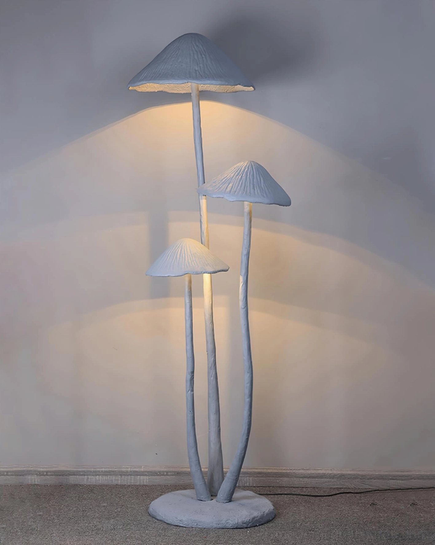 Modern mushroom floor lamp with warm LED glow in interior space, front low-angle view showing three shade details