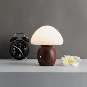 Mushroom table lamp on bedroom nightstand with warm glowing light, alarm clock and plumeria flower decor