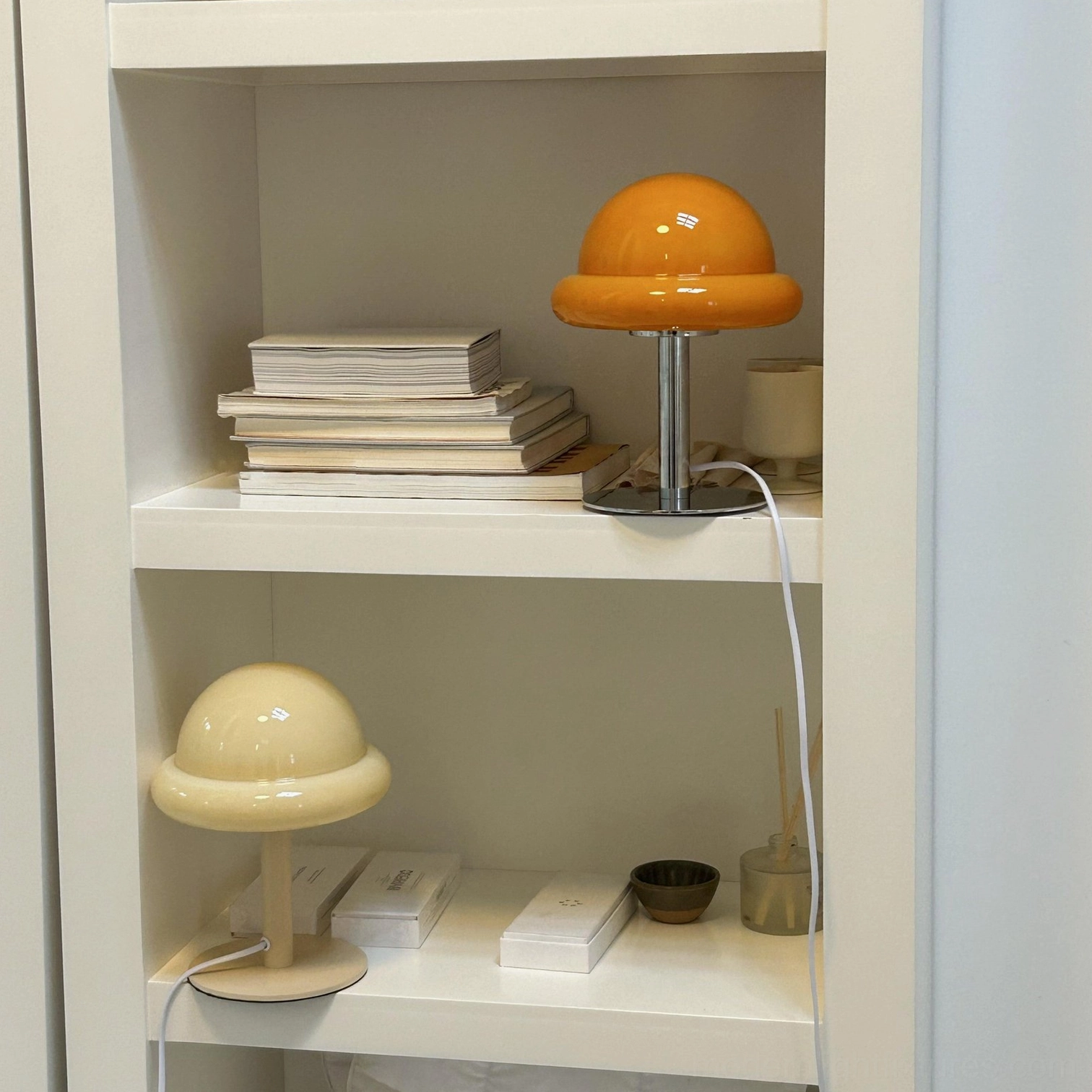 Kleine mushroom table lamps in multiple colors displayed on built-in bookshelf with books and ornaments
