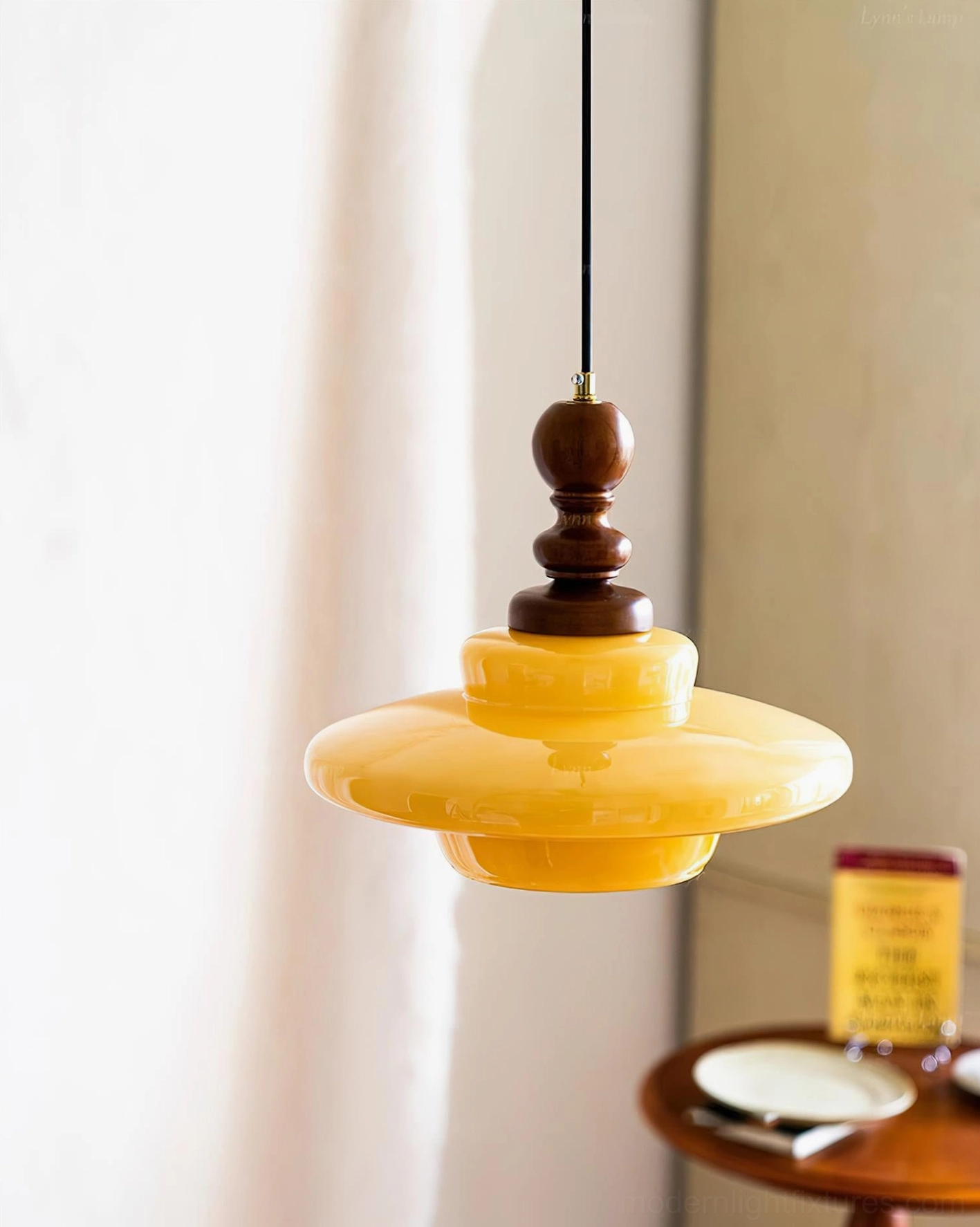 Mid-century modern yellow glass pendant light suspended above dining table, side angle view showing retro design details