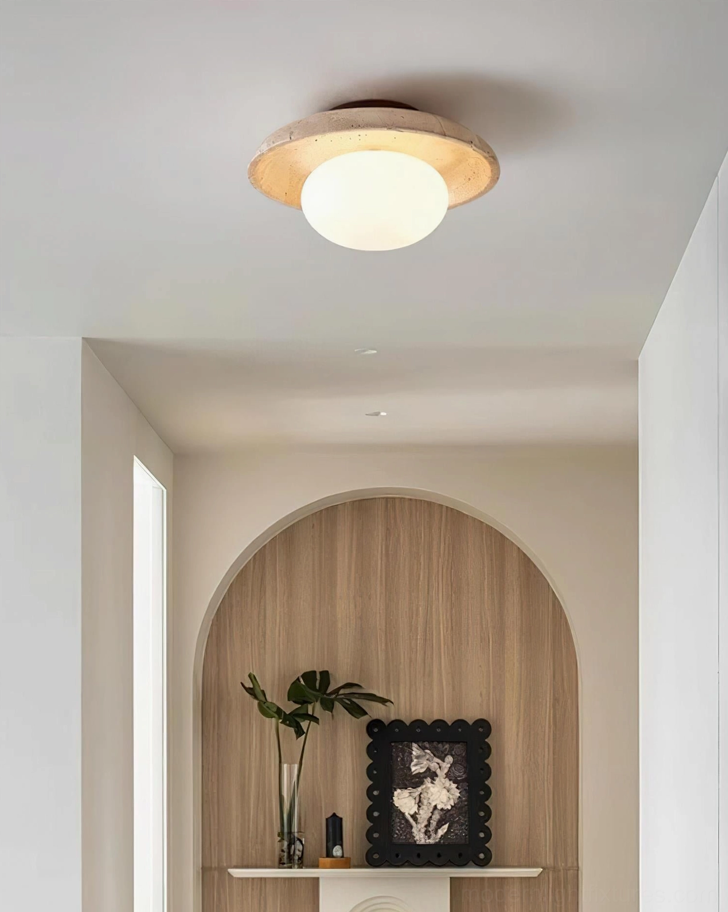 Mylie travertine ceiling lamp glowing in residential hallway with arched architectural detail and mid-century warm lighting