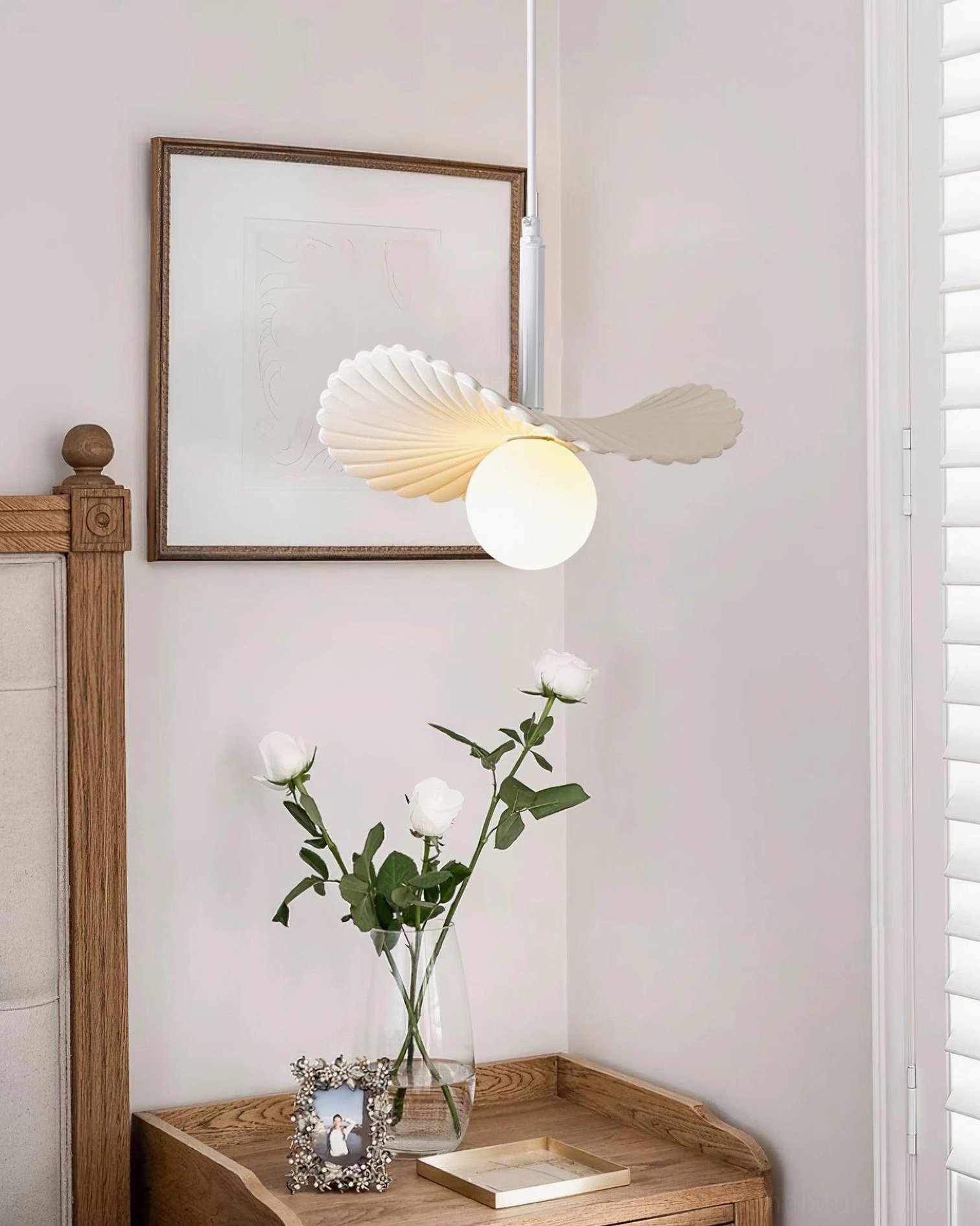Cream frosted Myrna pendant light above bedroom nightstand with wall art and floral table decor, intimate bedroom corner lighting