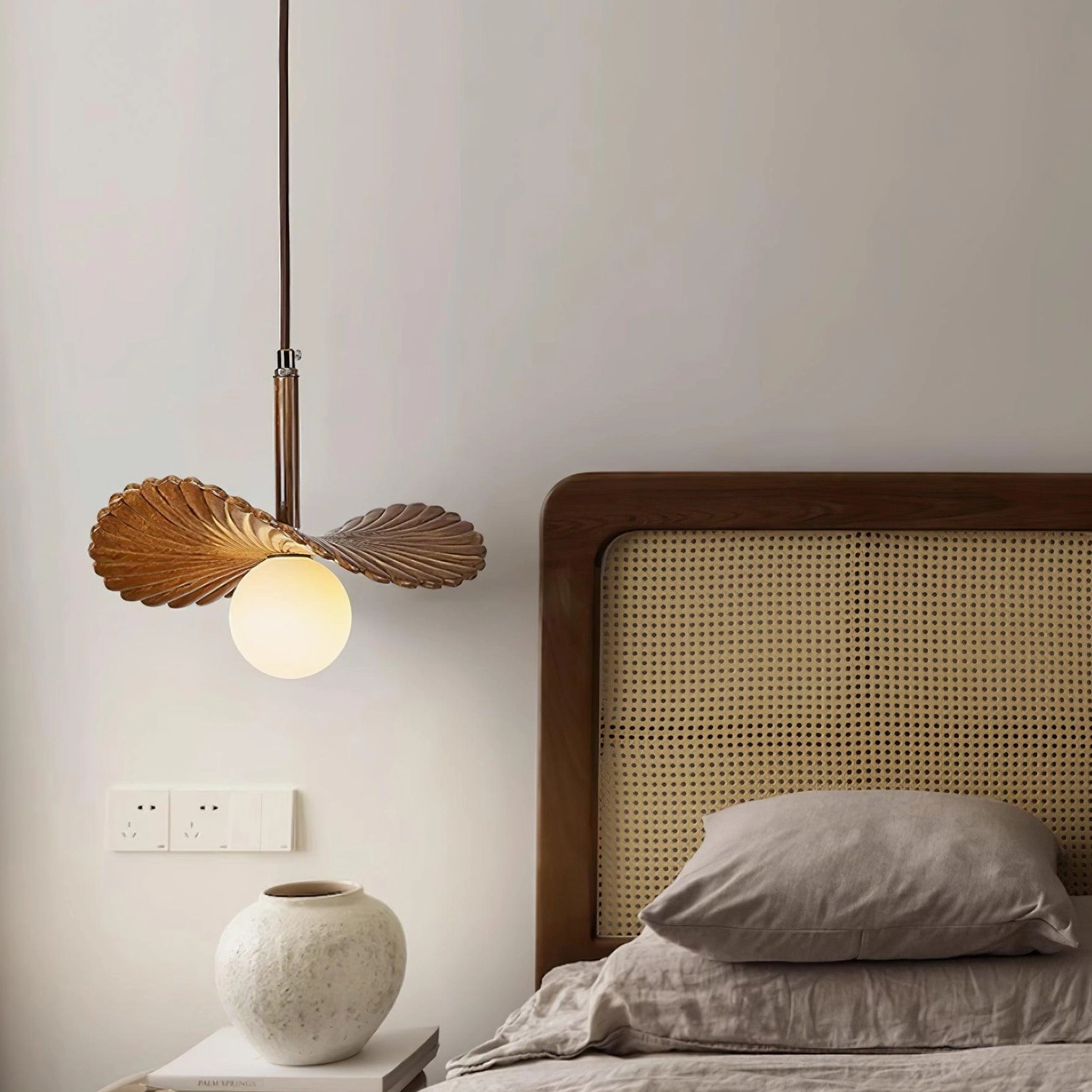 Wood-toned Myrna pendant light installed in cozy master bedroom with rattan headboard, wabi-sabi inspired bedroom ambiance