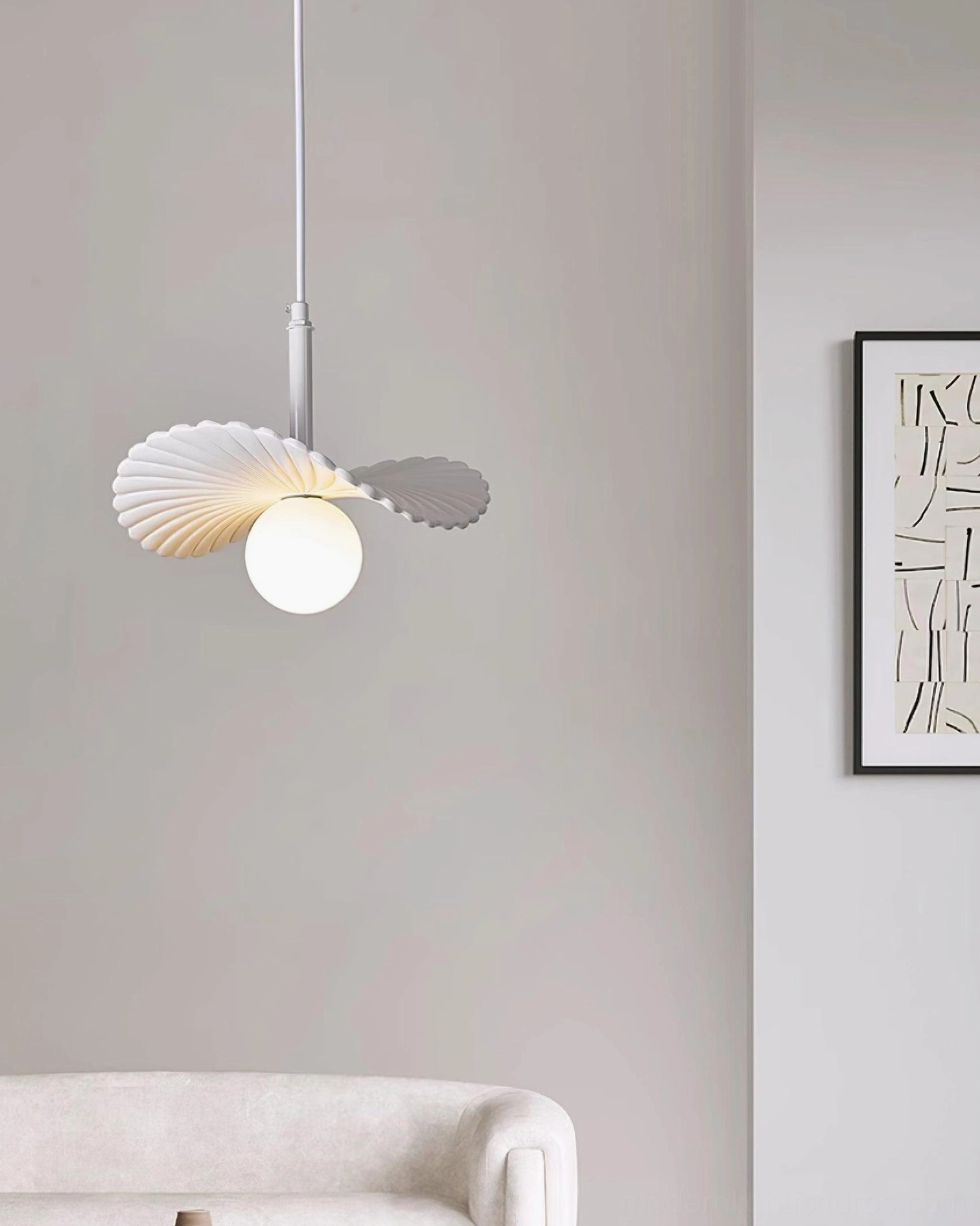 Myrna pendant light installed in modern living room with sofa and wall art, showcasing warm minimalist Nordic interior design aesthetic