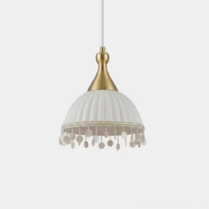 Nacara shell fringe pendant light close-up studio shot showcasing white ribbed ceramic dome, brass gourd-shaped hanger, and hand-strung natural shell disc fringe