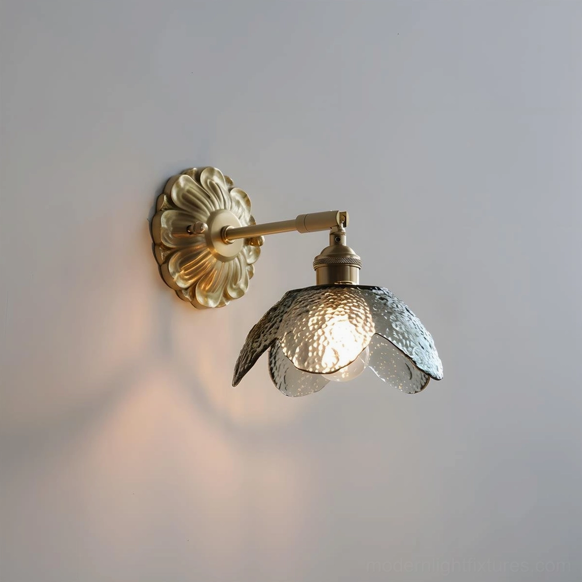 Nacre Petal Wall Sconce with smoky gray glass petals, brass fixture illuminated, close-up artistic view
