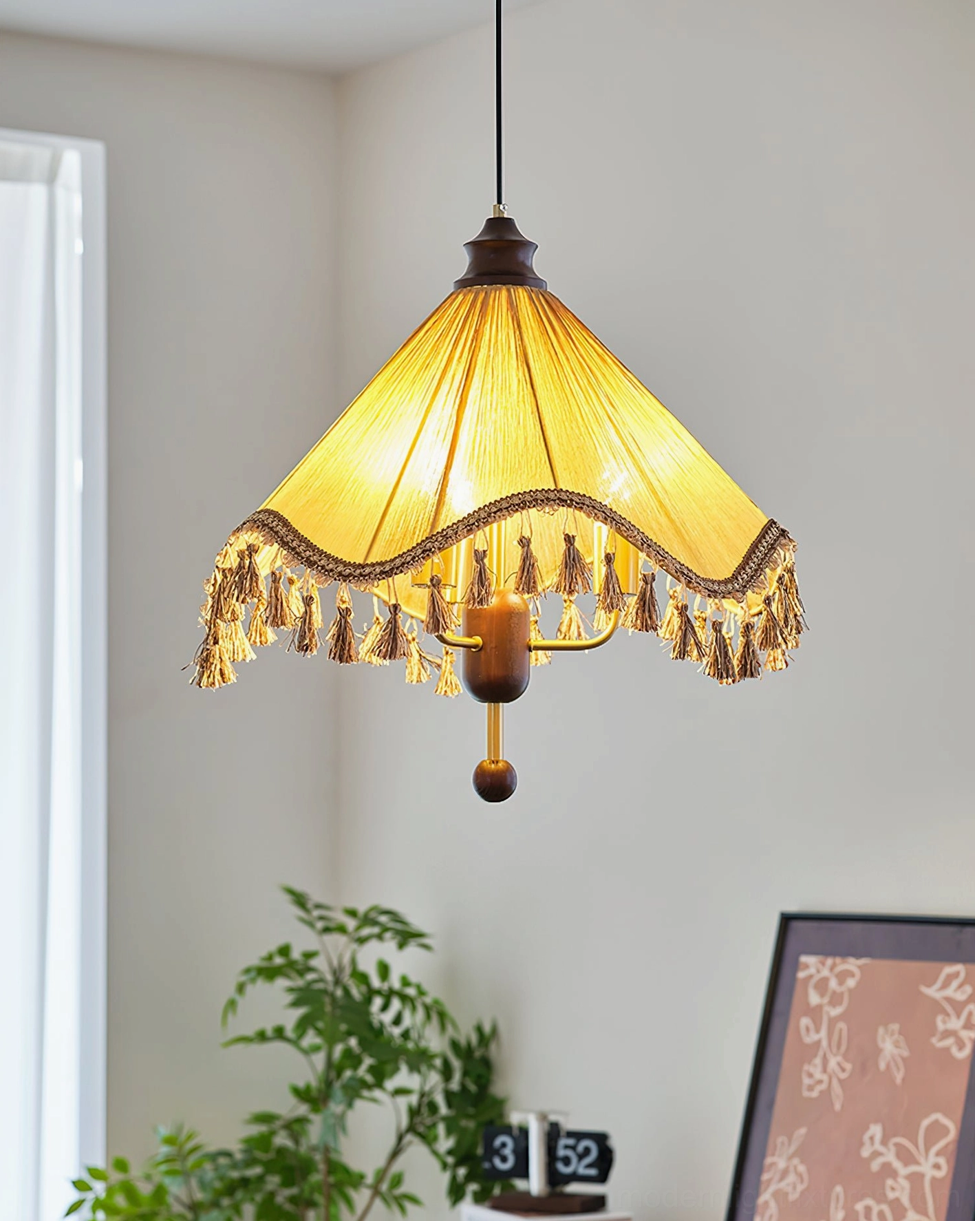 Nadia pleated pendant light with exposed candle bulbs and walnut-toned base installed in residential bedroom corner with green plant decor