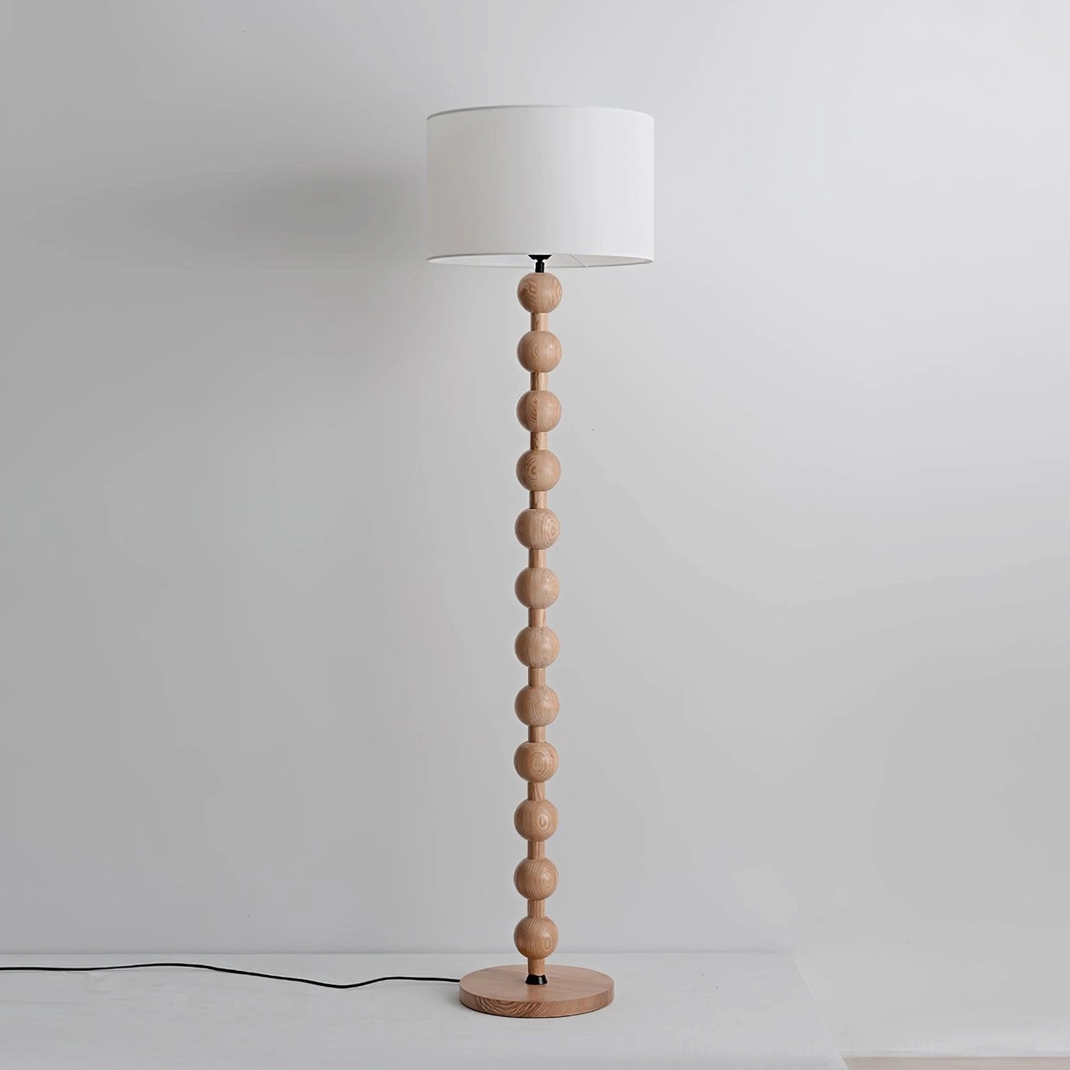 Natural light wood barbell floor lamp with round base and off-white fabric shade