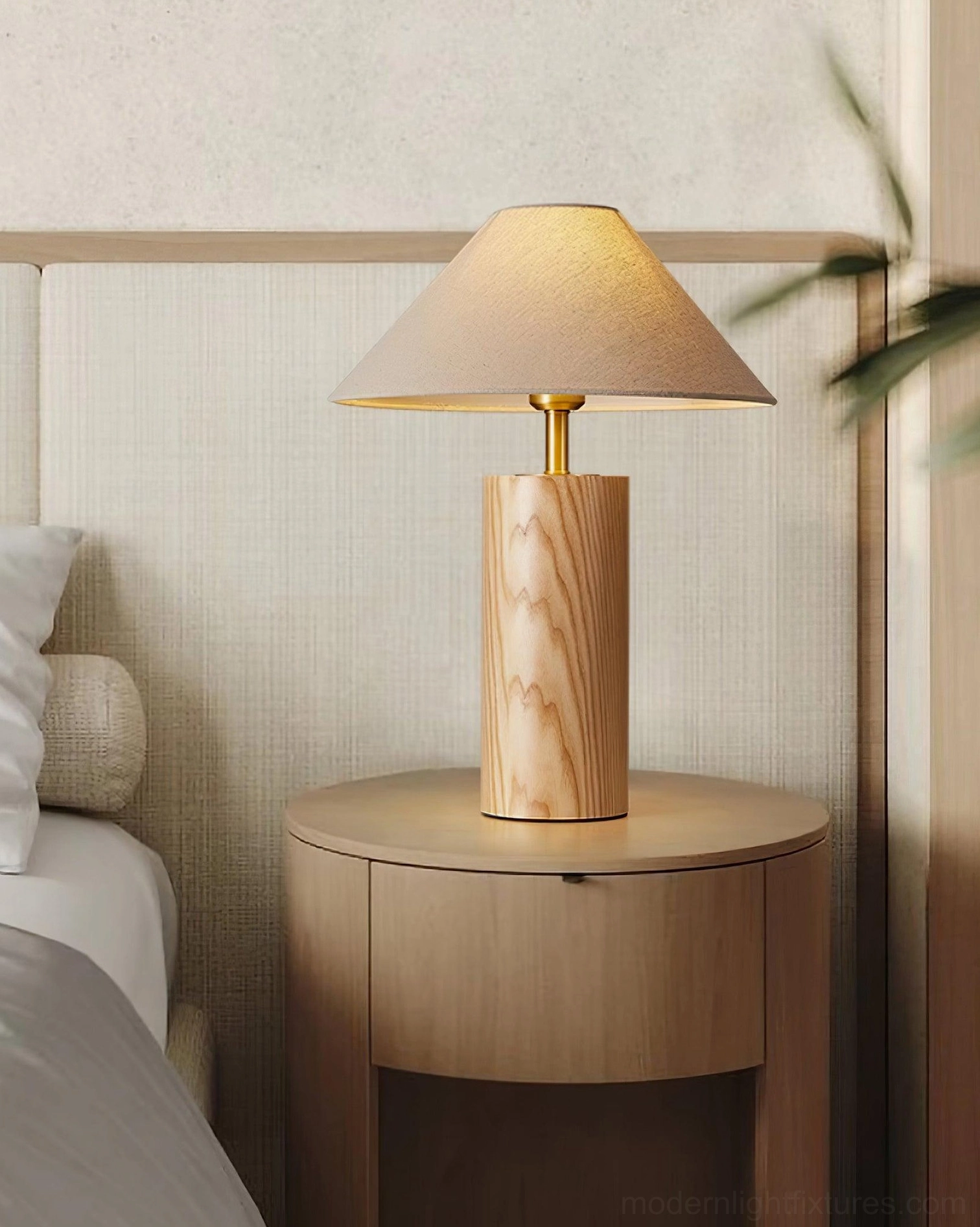Natural wood cylindrical table lamp on round wooden nightstand in serene bedroom setting