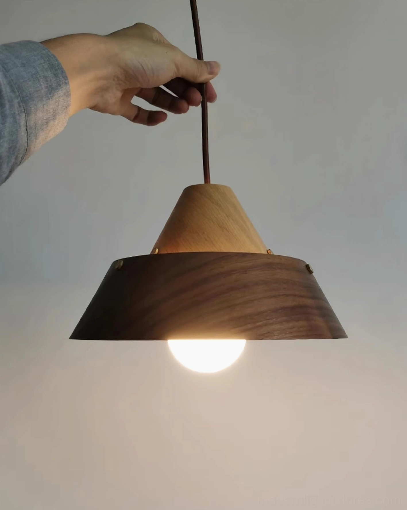 Natural wood finish tiered pendant light in Scandinavian minimalist dining space with organic material palette