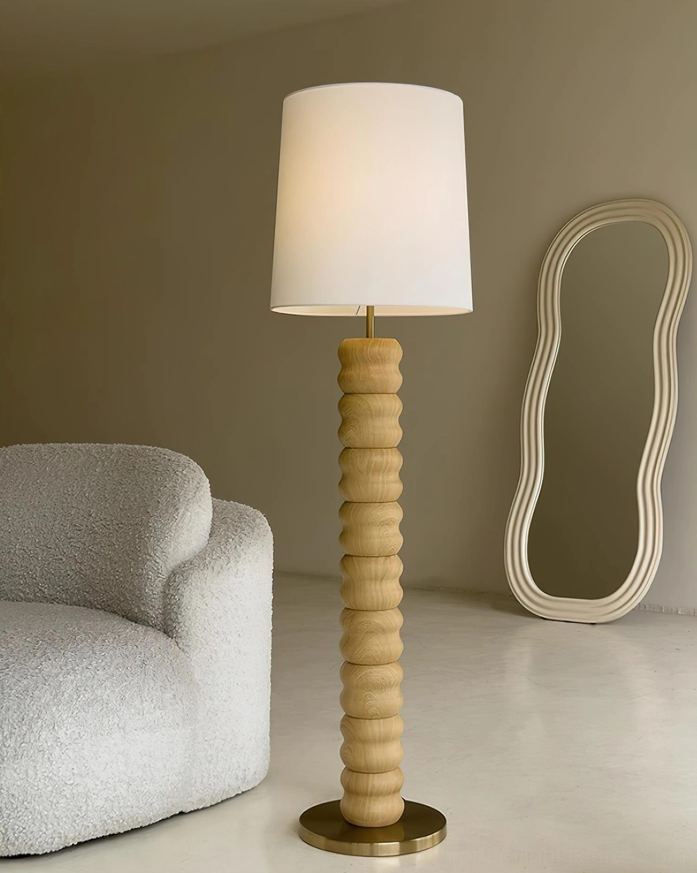 Light wood stacked floor lamp with brass hardware in cozy living room with curved decorative mirror