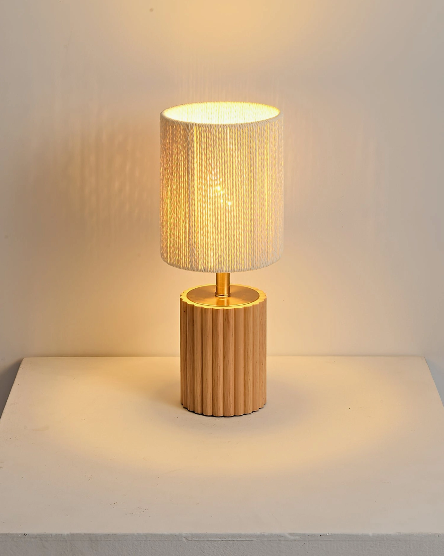 Natural light wood fluted base table lamp with warm glowing textured shade on tabletop