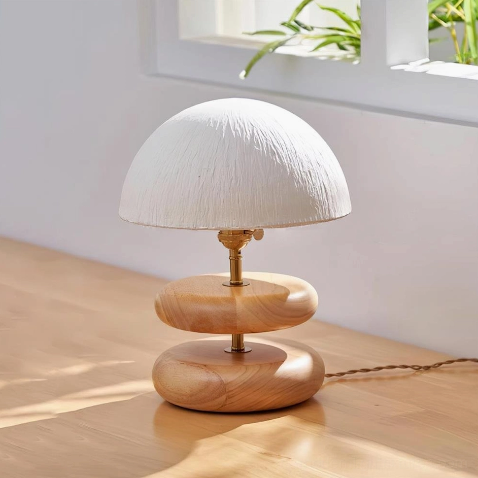 Natural wood tone stacked ring table lamp three quarter view beside window with green plants Scandinavian style