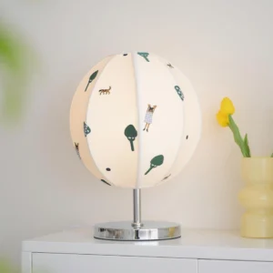 Contemporary printed fabric table lamp displayed on white dresser with yellow tulip vase, three-quarter angle showing spherical shade design