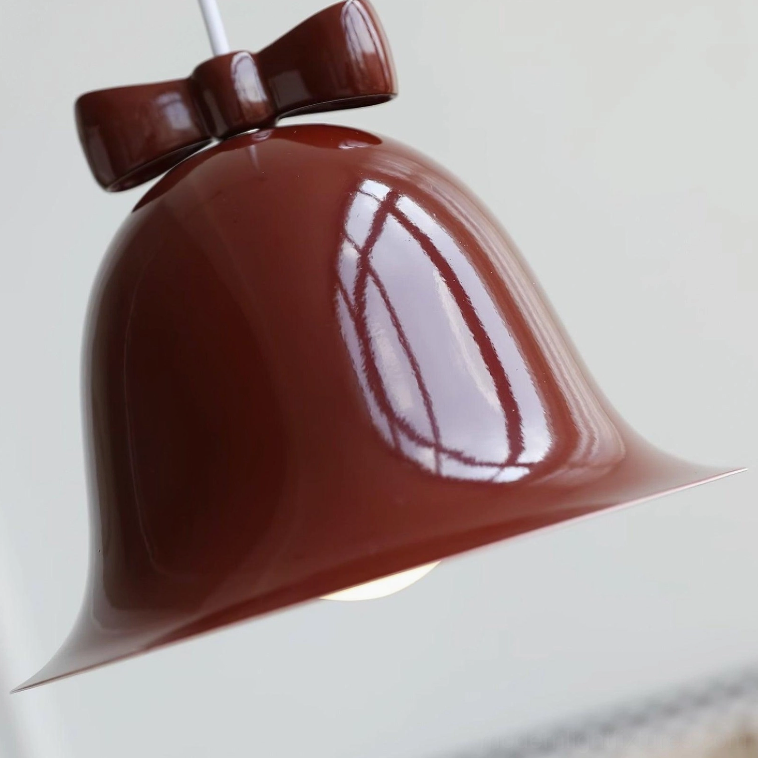Navy blue ceramic bell-shaped pendant light with brown bow detail studio photography