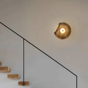 Nebulae glass wall sconce in modern staircase hallway interior design - warm ambient lighting on light gray wall