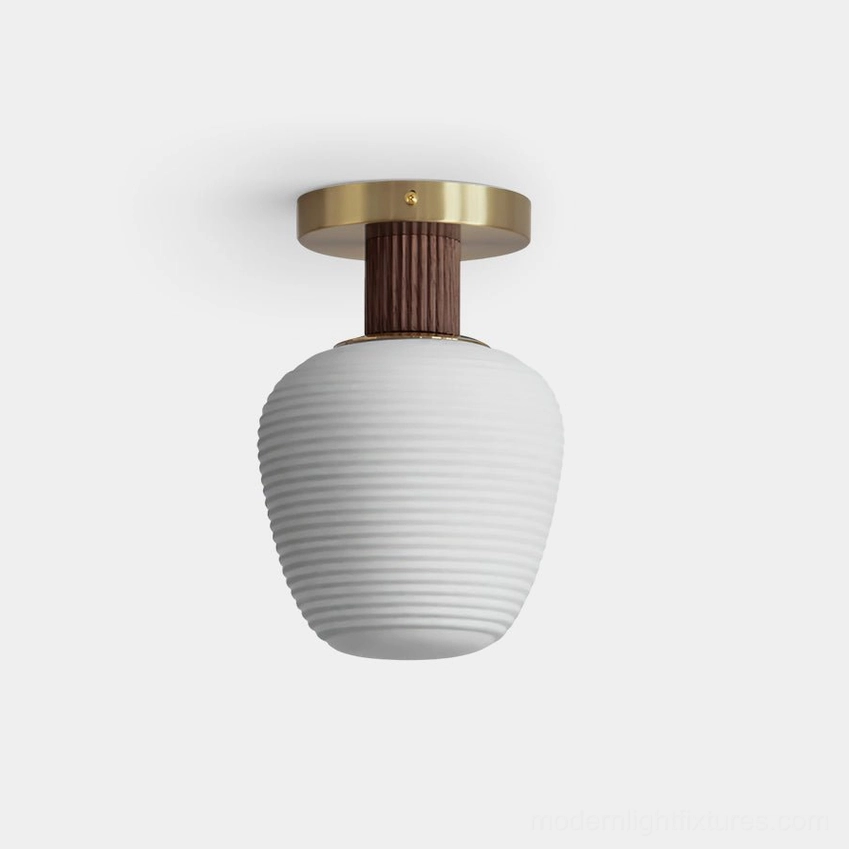 Neroma frosted glass ceiling light fixture with ribbed ceramic shade, brass metal canopy, and wood accent connector in studio view