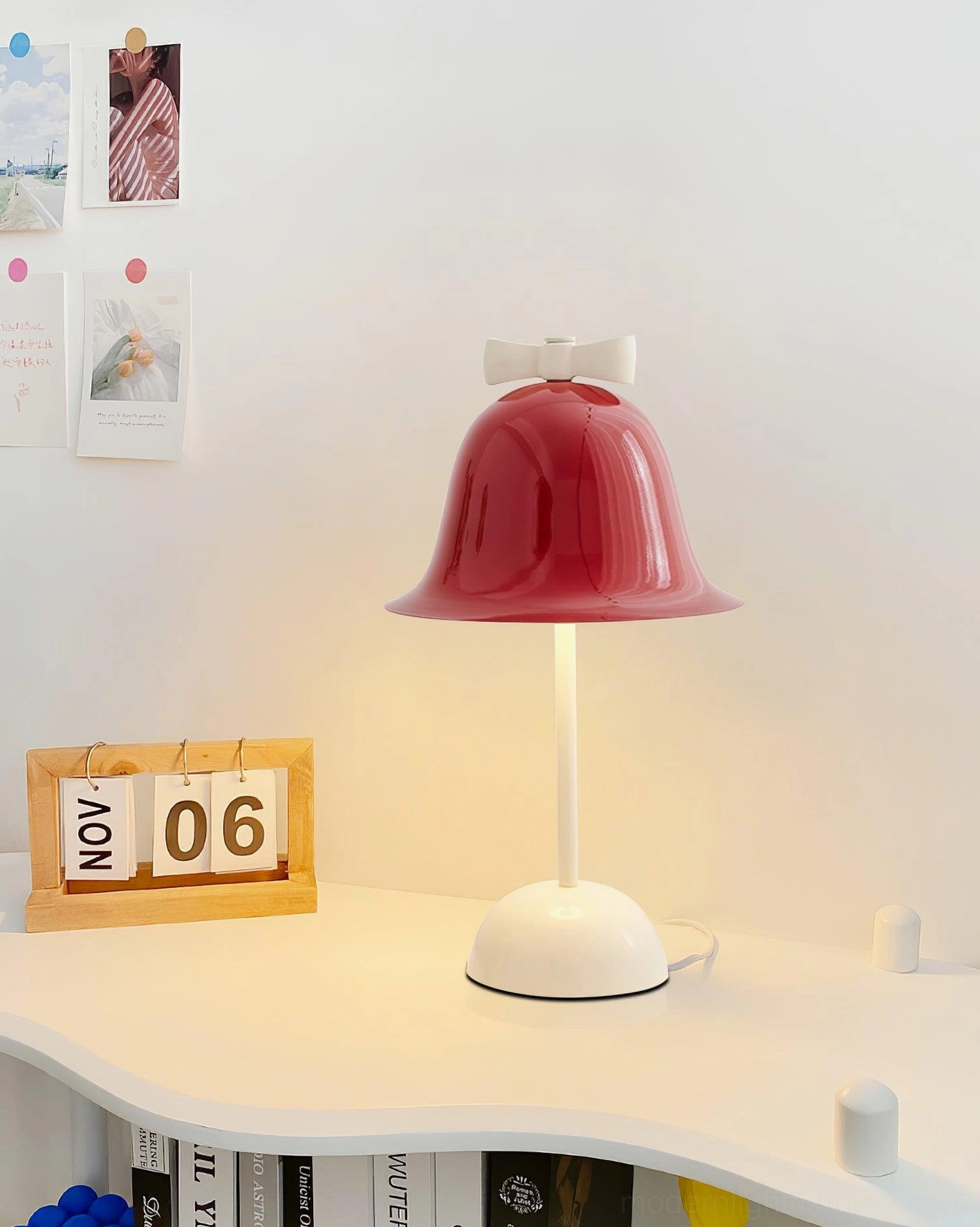 Designer table lamp on white desk workspace with wooden calendar and wall photo stickers
