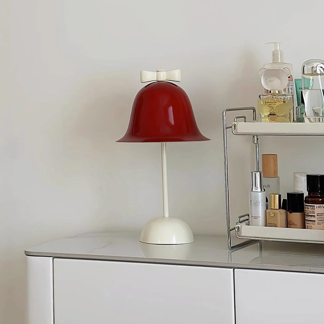 Red wine shade table lamp on bedroom dresser next to skincare storage and personal items