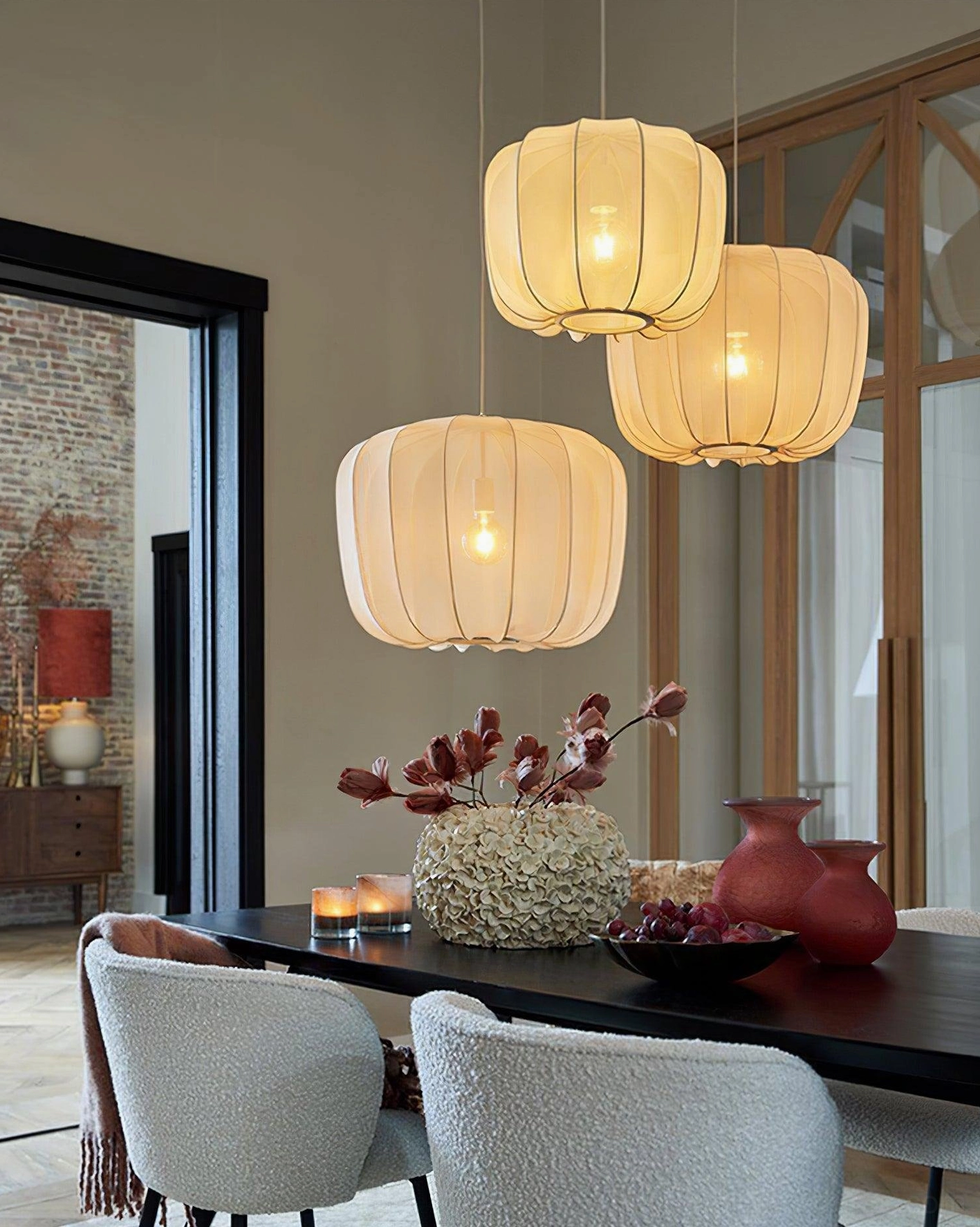 Three light yellow Nevola fabric pendant lights hanging in dining room, warm ambient group lighting installation