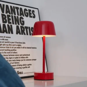 Red rechargeable LED table lamp displayed on side table beside art poster home decor
