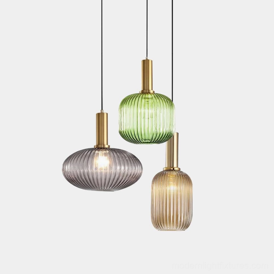 Three ribbed glass pendant lights in mixed sizes and colors displayed on white studio background - green, cognac, and smoke gray modern pendant lamps