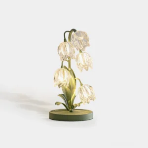 Niya botanical green table lamp with glass petal shade on white studio background, front side view showing sage green metal stem and warm ambient glow
