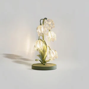 Modern floral green table lamp with clear glass petals and metal base, studio product photography with cast shadow on light gray backdrop