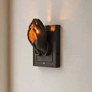 Noctara wall-mounted sconce with black hands cradling warm light in minimalist modern interior
