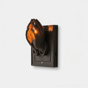 Noctara sculptural praying hands wall sconce with matte black finish and warm interior light glow