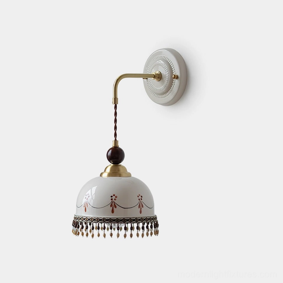 Noemi vintage ceramic wall sconce with hand-painted garland motif and beaded fringe trim, antique brass fittings, studio front view