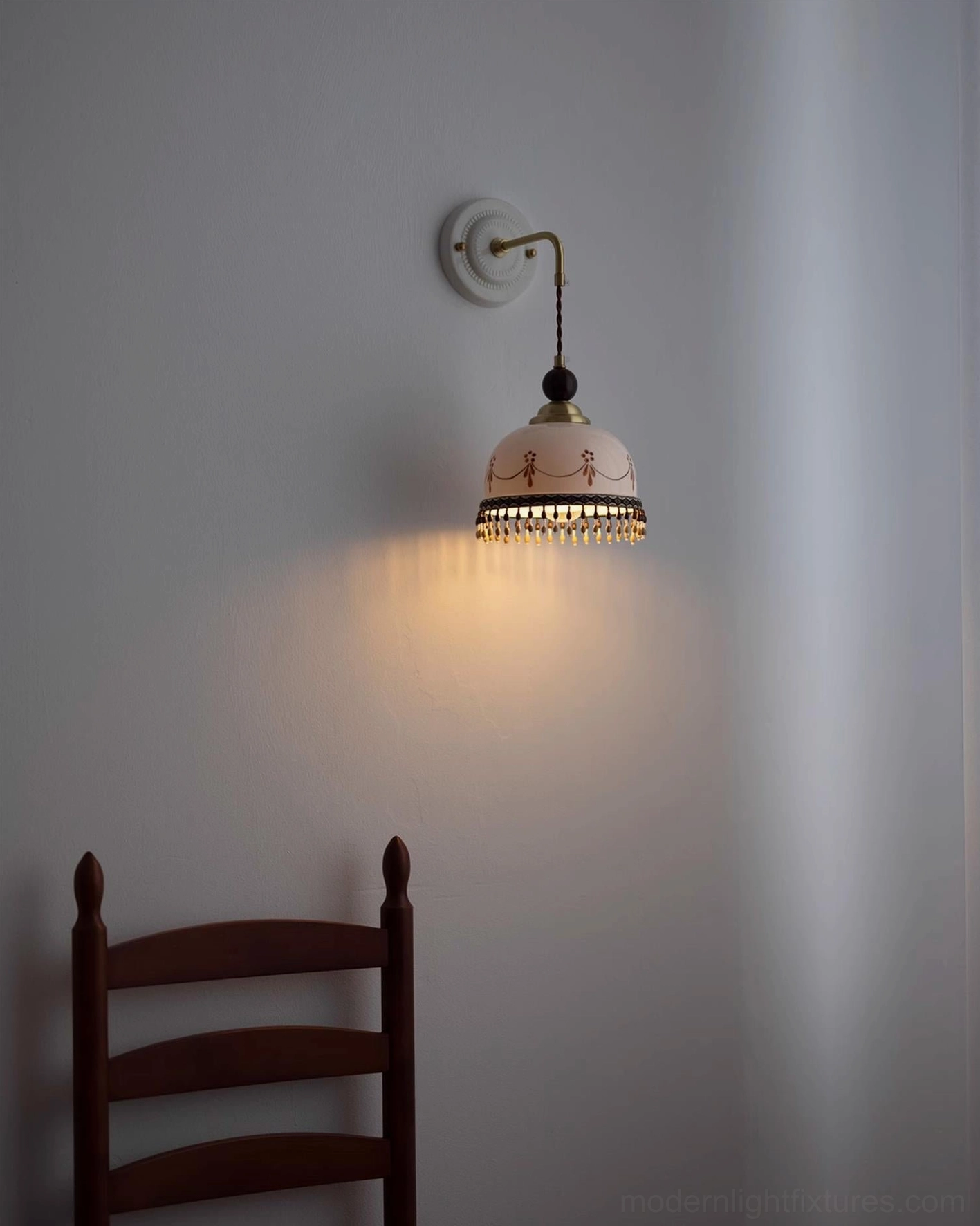 Compact Noemi pink ceramic wall sconce, minimalist interior corner, wooden chair, warm retro bohemian lighting, side angle