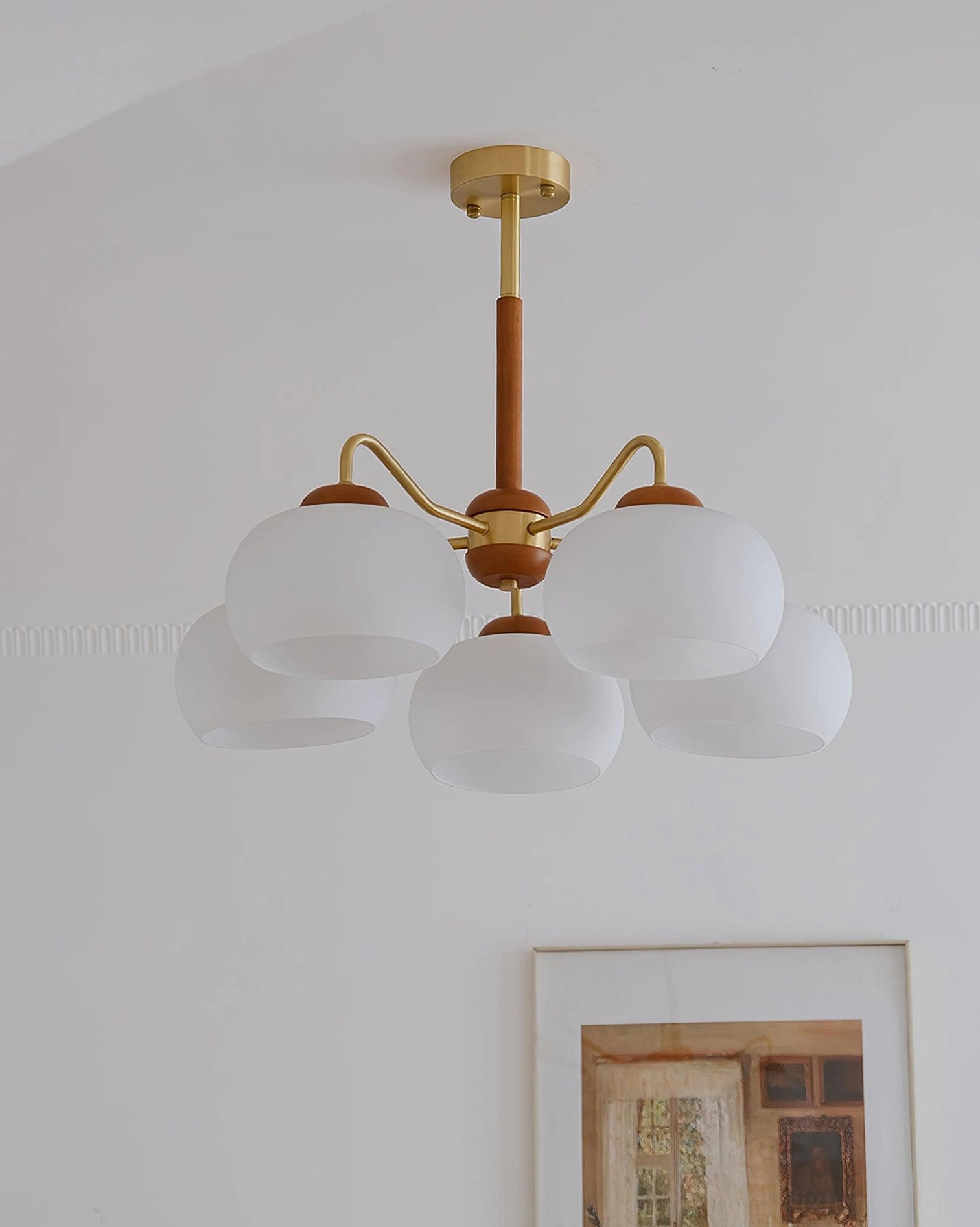 Modern Nordic glass and brass chandelier pendant with frosted shades in minimalist interior with framed wall art