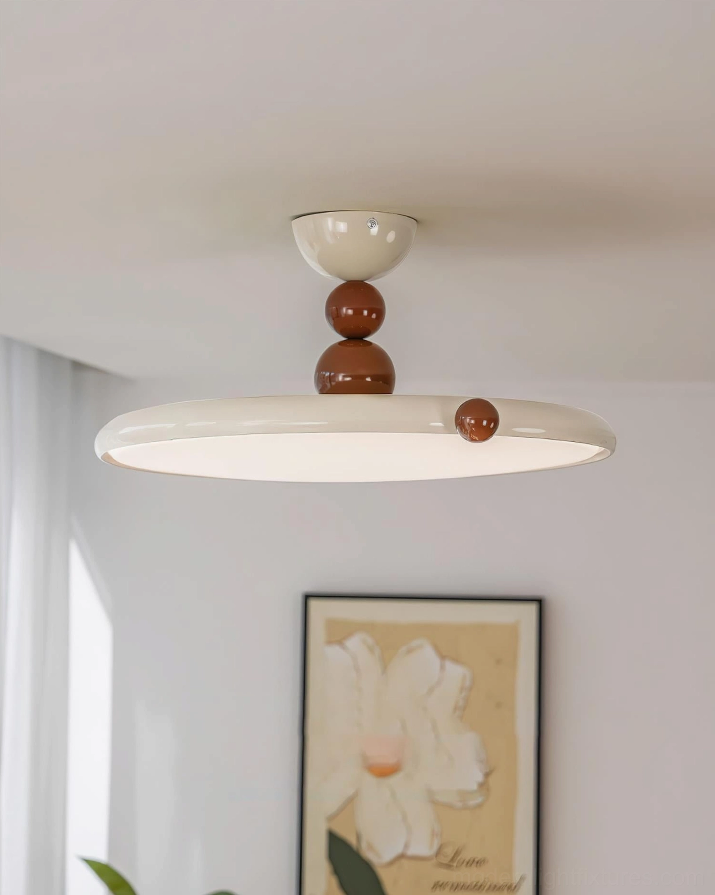 Modern minimalist ceiling lamp in Nordic cream aesthetic, low-angle side view in residential room with floral wall art