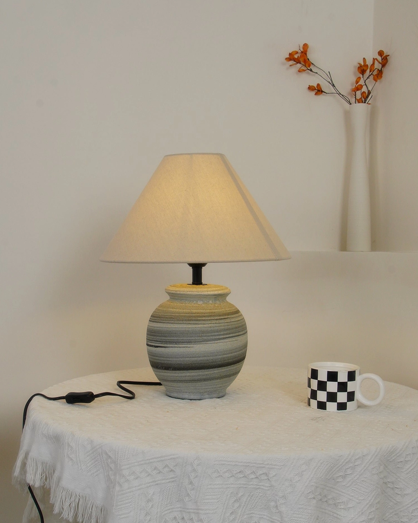 Norma table lamp with tapered linen shade creating warm intimate atmosphere in reading nook setting