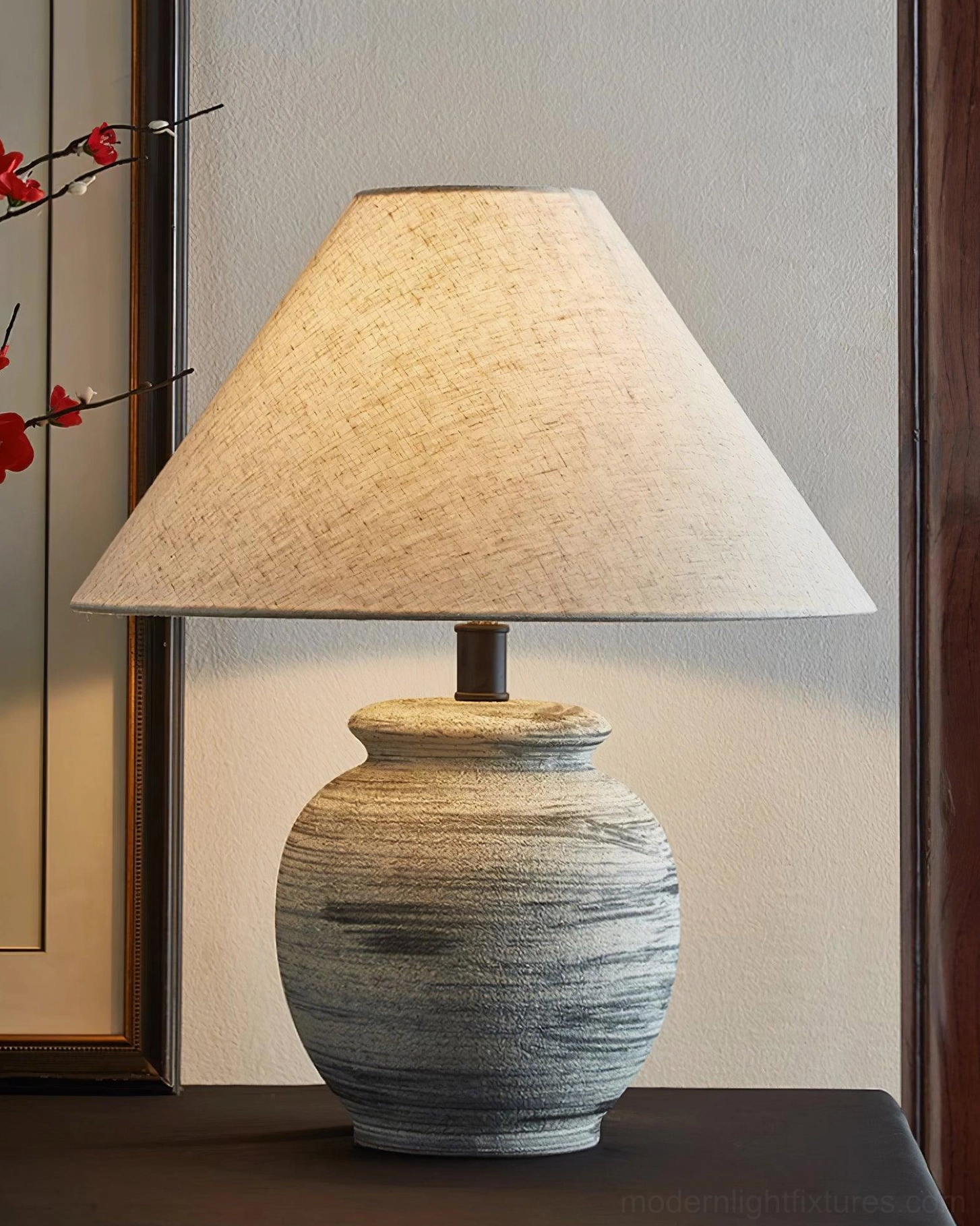 Norma table lamp on side table styled with pottery, books, and natural decor elements