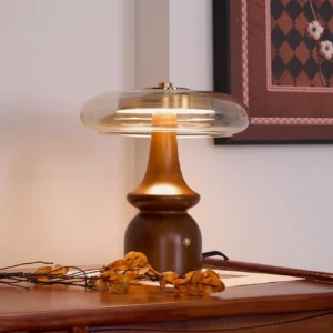 Nova retro table lamp illuminated on bedside table with warm cognac glass shade creating cozy ambient lighting and dried floral decor