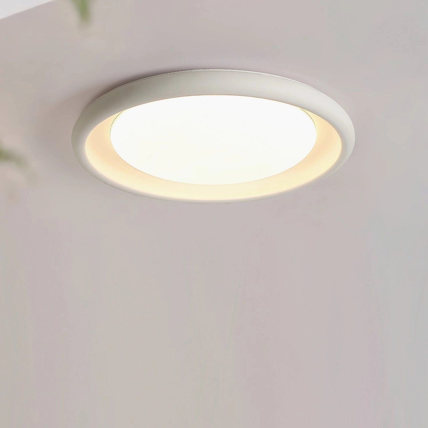 White modern flush-mount ceiling light fixture, high-angle overhead shot on plain ceiling background