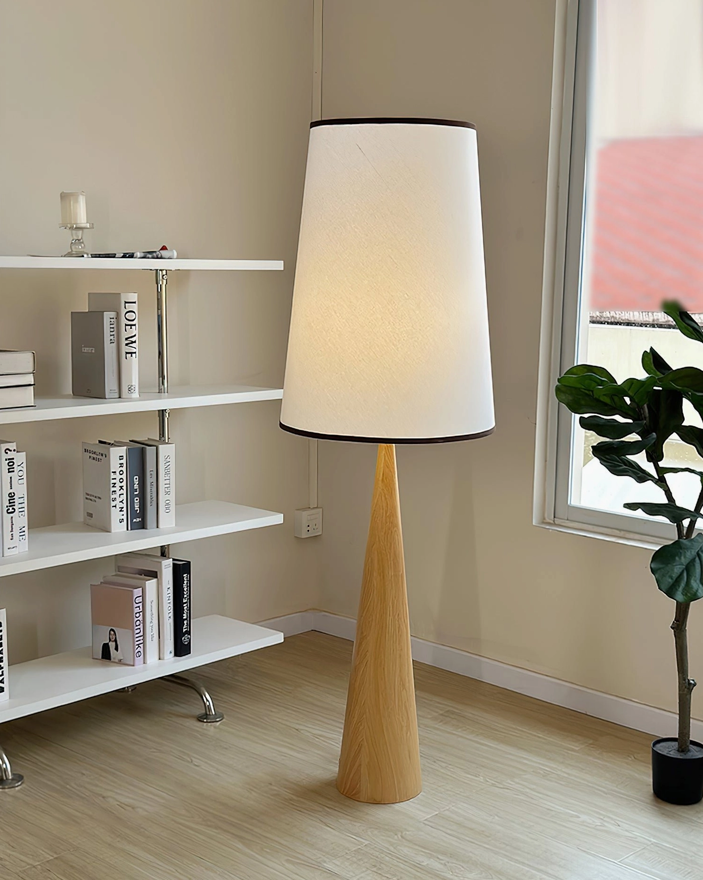 Light oak contemporary floor lamp positioned beside bookshelf and potted plant for ambient home office lighting