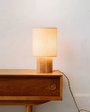 Warm glowing oak wood bedside table lamp on bedroom nightstand - soft light diffusion for reading