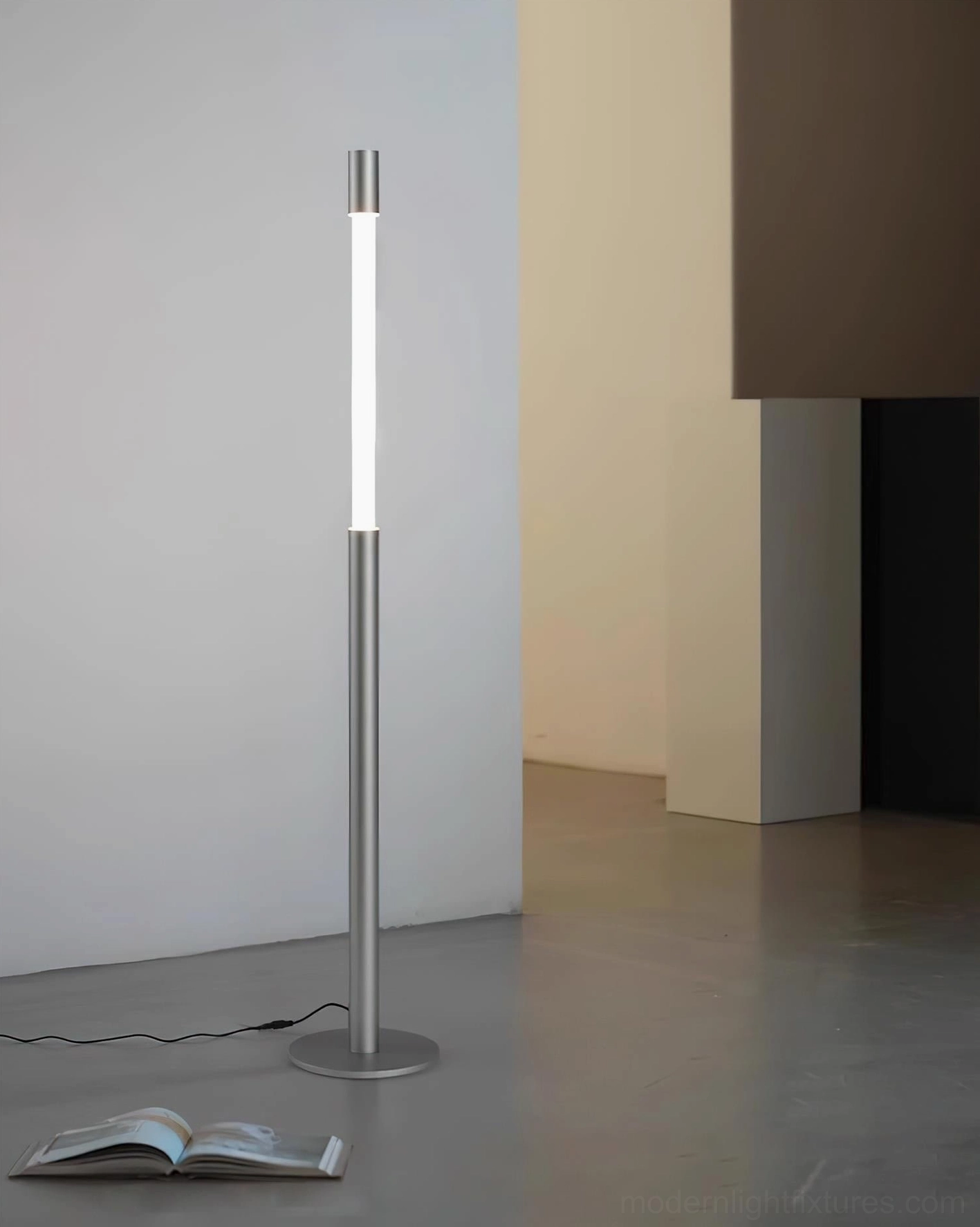 Obelisk silver minimalist floor lamp with soft LED glow beside modern furniture and open book