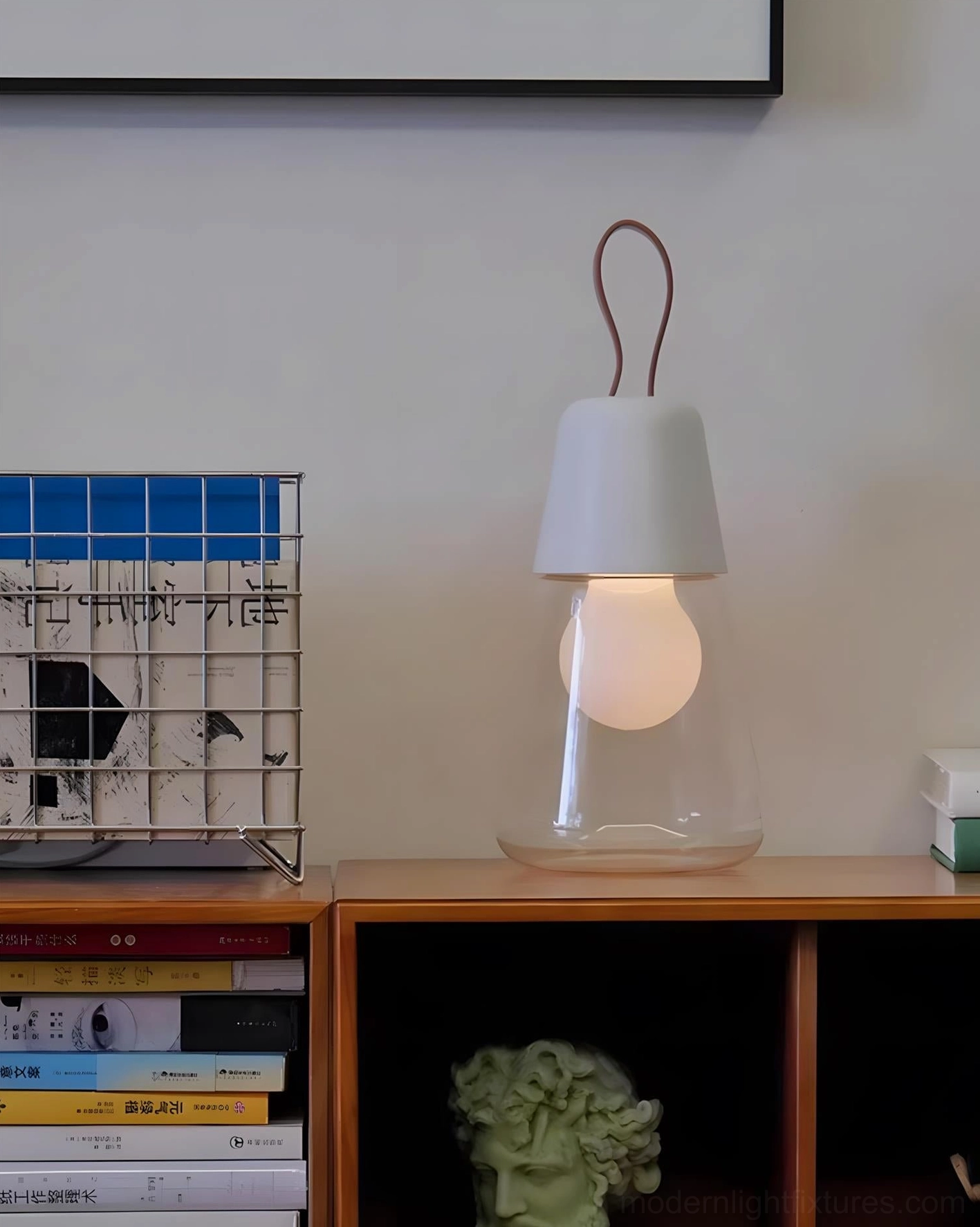 Light gray Oceana portable table lamp displayed on wooden side cabinet in modern living room interior