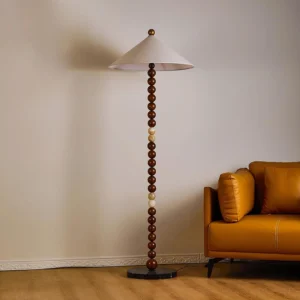 Octavia floor lamp in living room, three-quarter view showing walnut color pole and marble base with fabric shade