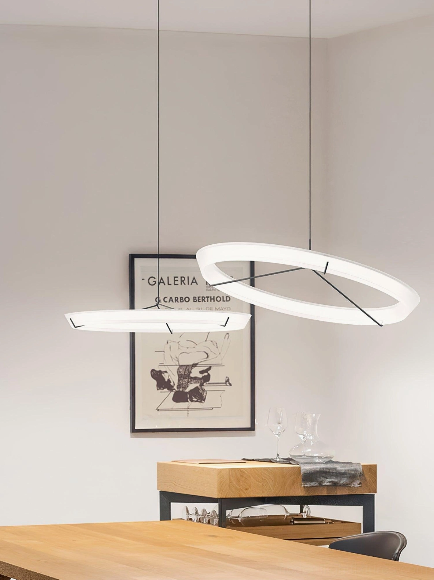 Two offset round LED pendant lamps with frosted rings and art wall decor in minimalist dining room