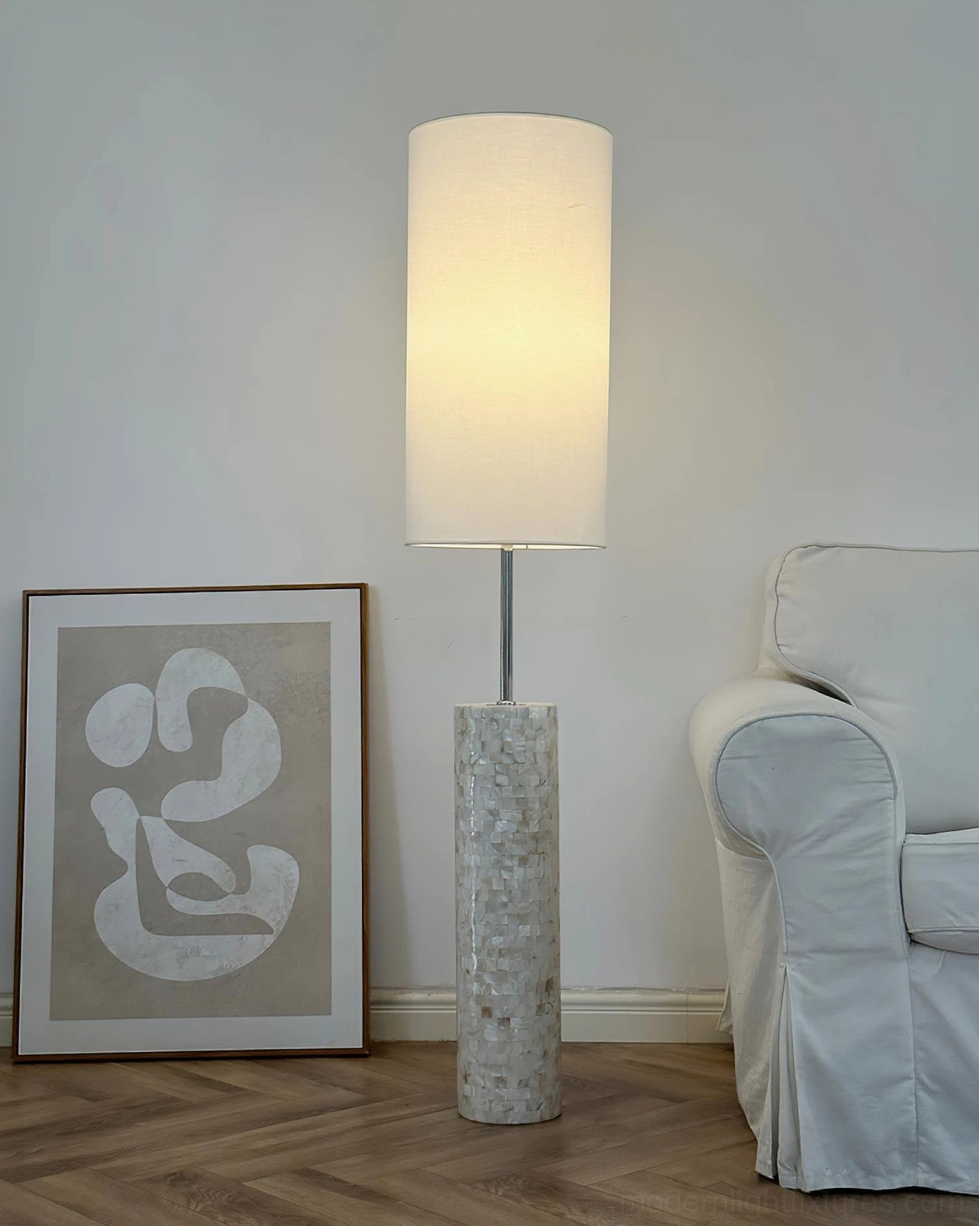 Ollie modern floor lamp providing warm ambient light in contemporary living room with artwork and sofa