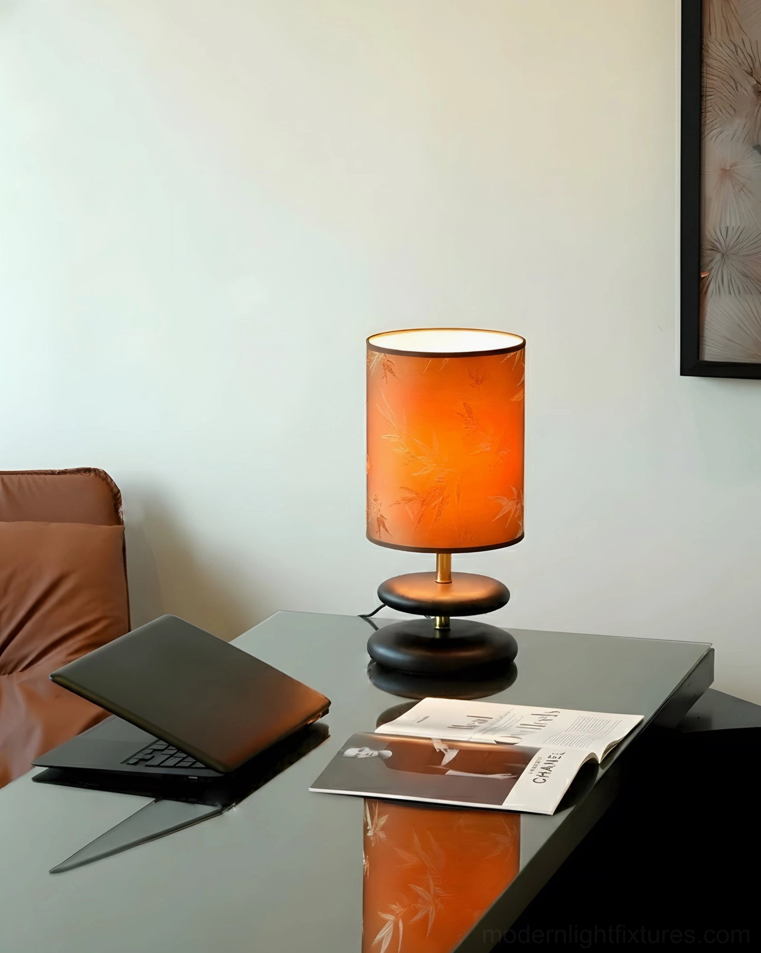 Orange bamboo-pattern table lamp on home office glass desk, three-quarter side view with dark wood and gold base