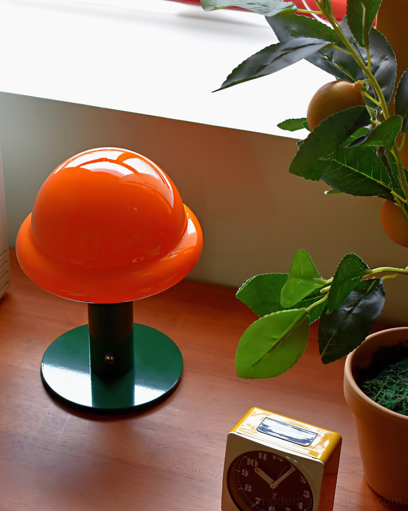 Orange glossy mushroom rechargeable lamp on wooden desk with small clock decor and potted plant