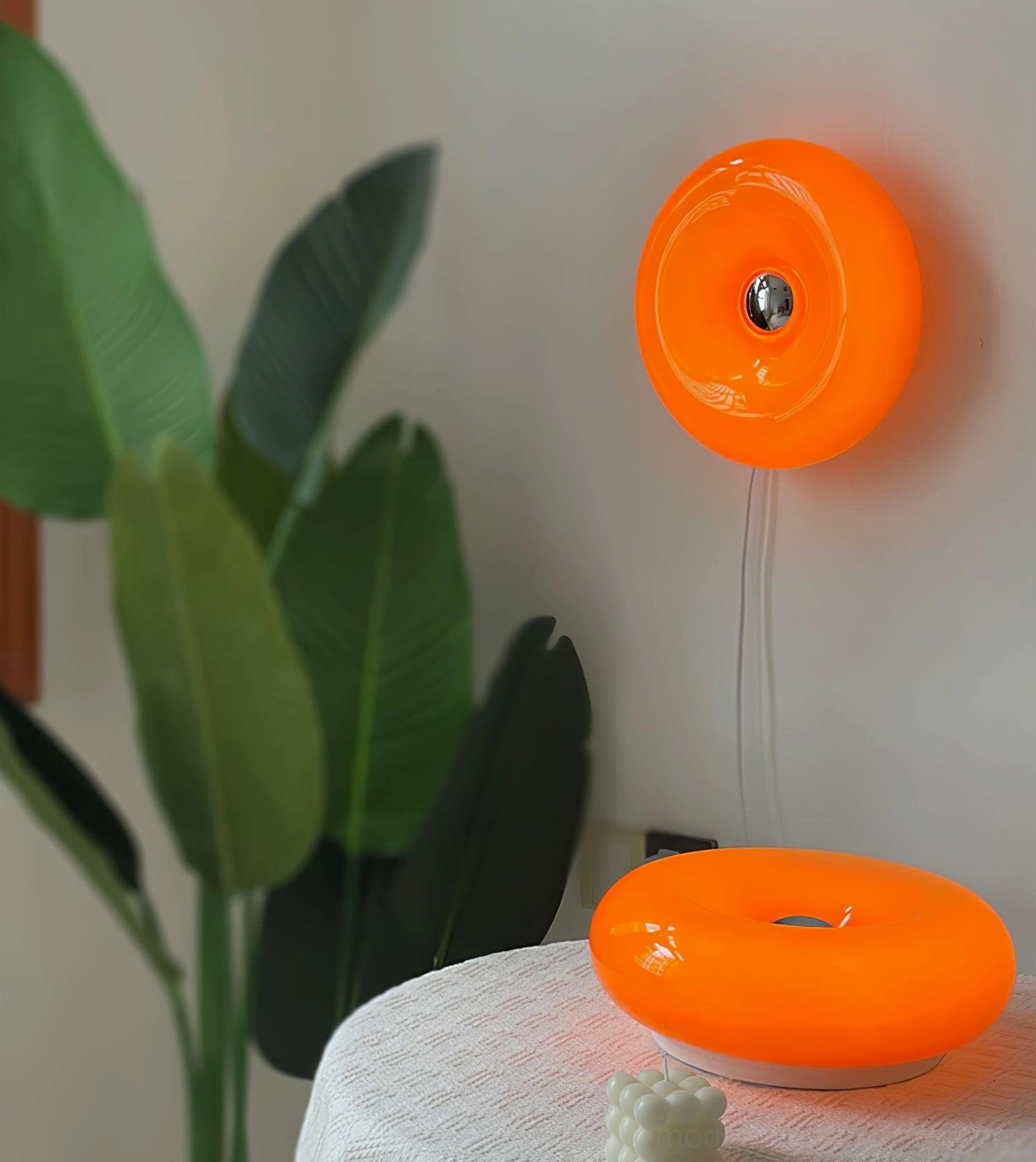 Vintage-inspired orange donut wall sconce mounted on light wall, showing diffused warm glow